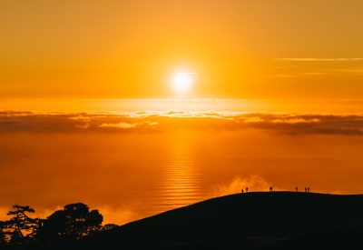 people on top of hill under white clouds golden hour photography